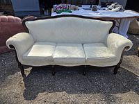 Front view of white vintage three-seat couch showing dark wood frame and worn cushions