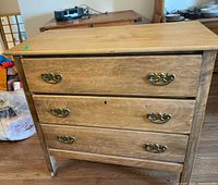 Front view showing three drawers, metal hardware, casters