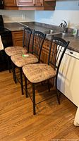 Three black metal bar-height chairs beside kitchen counter