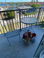 Table, chair, planters, watering cans on balcony