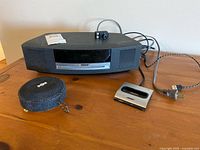 Front view of Bose Wave Music System with power cord, portable round speaker, and Bose iPod dock on tabletop