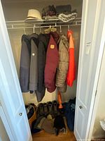 Overview of closet showing six coats, hats, scarves, gloves, boots, umbrella