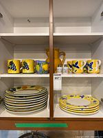 cabinet view showing mugs, pitcher, plates