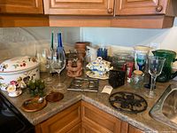 Overall view of assorted decor on countertop showing glassware, ceramics, trivets and metal lantern
