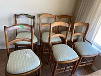 Six wooden dining chairs with striped seats grouped in room
