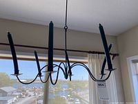 Chandelier hanging with six green taper candles attached