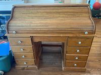 Front view showing roll-top closed and nine drawers with white knobs
