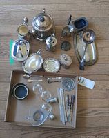 Overhead view of all silver-plated pieces including teapot, gravy boat, tray, ladle and box of small items