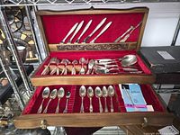 Open two-tier chest displaying assorted flatware pieces