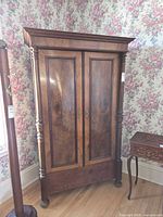 Front view of wooden 2-door armoire showing doors, veneer, columns and feet