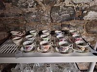 All twelve teacup and saucer sets with cream and sugar pieces displayed on shelf