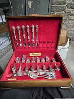 Open chest showing knives, forks, spoons in red felt interior