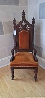 Front view of carved high-back armchair with burnt orange upholstery