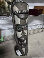 Full view of carved wooden African tribal mask standing on base