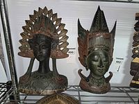Front view of both wooden bust sculptures on shelf