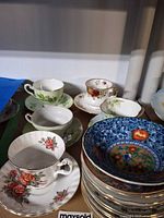 Five teacup and saucer sets with one stack of extra saucers visible