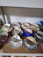 Group shot of all nine cup-and-saucer pairs on shelf