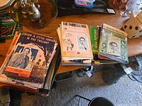 Two stacks of assorted vintage sheet music; visible titles Linger a Little Longer in the Twilight, The Umbrella Man, Jean Fletcher piece, Sweet Surrender