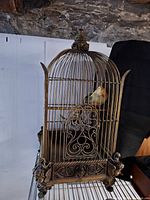 Full view of ornate metal birdcage with faux bird inside