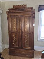 Front view showing inlaid double doors, crown, lower drawer