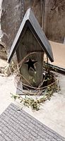 Front view of tall wooden birdhouse with star cut-out and grapevine wreath