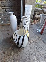 All four white ceramic vases grouped together on ground