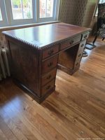 Front and side view of wood kneehole pedestal desk showing drawers and rope edge