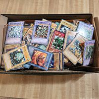 Top view of box filled with loose Yu-Gi-Oh! cards showing Blue-Eyes White Dragon and other cards