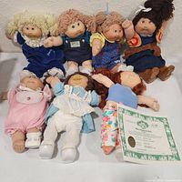 Group shot of seven Cabbage Patch Kids dolls showing outfits and accessories