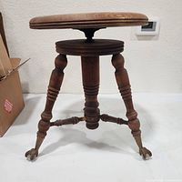 Full view of one wooden piano stool with claw feet