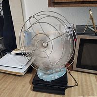 Front view of fan on desk showing overall appearance and cage