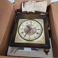 Clock in box showing face, wood frame, foam packing