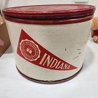Front view of cylindrical cream body with red pennant Indiana graphic and red lid