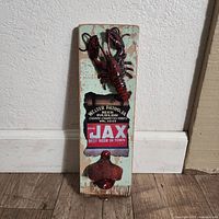 Full view of wall plaque showing wood board, crawfish figure, Jax Beer graphic, and bottle opener
