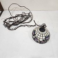 Lamp with long chain and cord coiled beside stained glass shade
