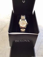 Bulova two-tone wrist watch inside open presentation box