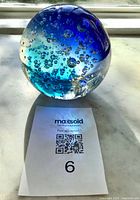 Overall view of blue glass sphere paperweight on marble surface