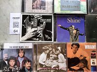 Group shot of several CD cases including The Best of Enya, Talking Heads Sand in the Vaseline, Stevie Ray Vaughan Greatest Hits, Shine soundtrack, The Moody Blues Gold and Wham!