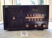 Front view showing entire radio with three knobs, speaker grill and dial