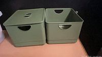 Two green plastic bins side by side, left with lid, right open