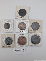 Group shot of seven penny coins in 2×2 holders with handwritten dates