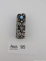 Front view showing grape motif and turquoise stone