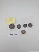 Group of five coins in sleeves with note and lot card