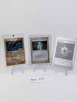 Three Pokémon cards in cases on stands