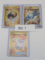 Front view of all three sleeved gold trainer item cards