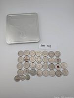 All loose coins arranged with metal tin above