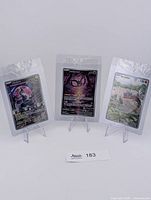 Front view of three sealed promo cards on stands