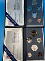 Both specimen sets open, showing coins and COA sheets