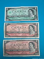 Front of three Canadian banknotes laid out: one $1 1967 Centennial and two $2 1954 series