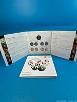 Open War of 1812 coin folder beside closed Canadian Flag folder